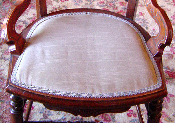 One of twelve matching chairs from Harrison's dining room. Walnut with seats and backs upholstered. Two carved spindle supports go across between the front legs. Two plain supports cross between the legs at the sides and back. Small side decorative supports (not Arms) go from the lower part of the back to the seat. The back, sides, and apron under the seat have an incised carved design. They are American Eastlake style dating from the 1870s.