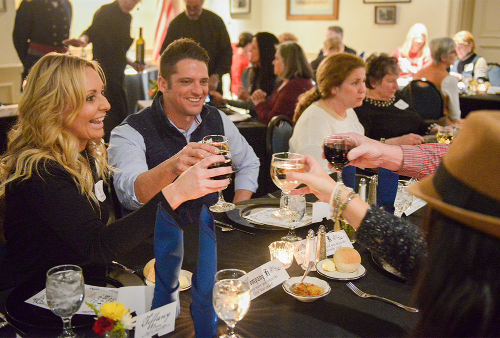 Photograph of a group of people at the civil war dinner toasting wine glasses.