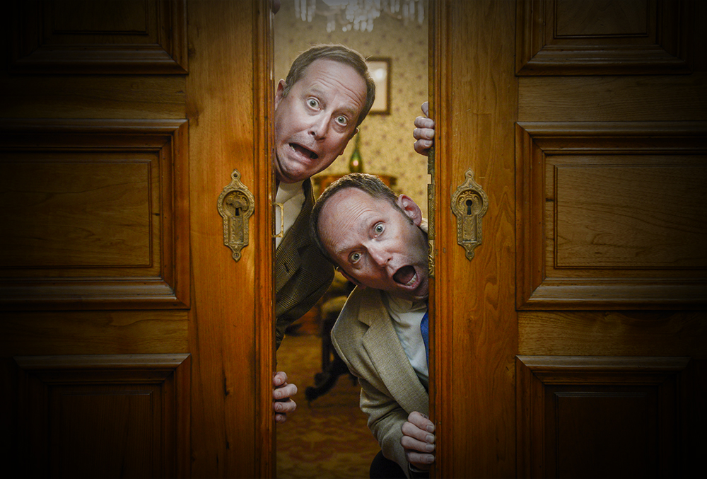 Photograph of two surprise men looking around the edge of a door.