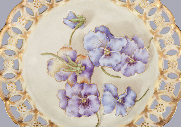 Designed and hand-painted by Mrs. Caroline Scott Harrison with hand painted purple and lavender Pansies. Edge is a cutout lace pattern with gold paint.