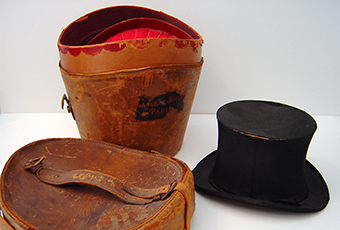 Opened view of the top hat case. Shows a red velvet interior shaped to accommodate the hat.