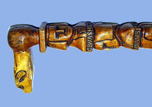 Centennial walking stick, contains hand carved images (head and shoulders in relief) of all the Presidents from Washington to Benjamin Harrison with name below each. They are on both sides of the cane coming down to Harrison. Wood is white pine and stained. The carved handle is an animal head design. Three of the president's names are misspelled: Madison, Hayes, and Arthur.