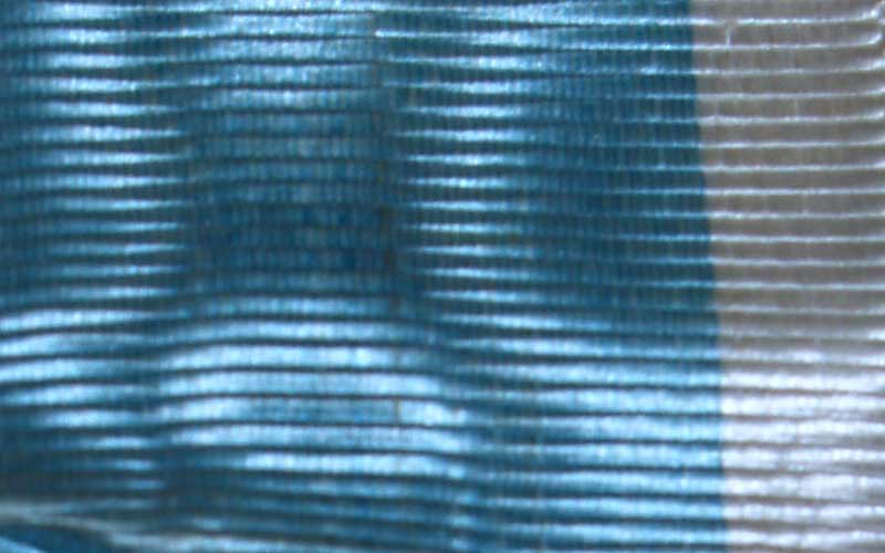 Closeup on the ribbon on the metal. Appears to be a sleek blue and white fabric with light bouncing off.