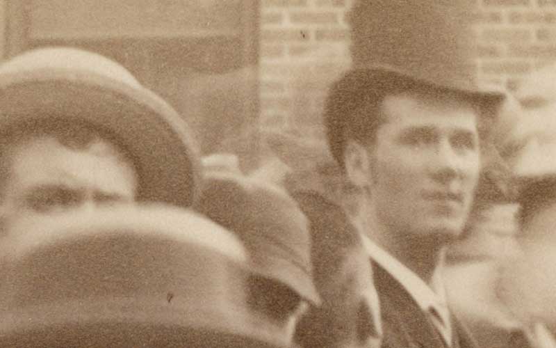 Photograph of crowd in front of Harrison's North Delaware Street home in 1888. Benjamin Harrison is standing near the front door slighlty to the left. Image shows the front of the house as it looked in 1888, picket fence at front sidewalk, and crowd of mostly men and young boys. A few women stand behind Harrison at the front door. The crowd is lined up on the rightside of the walk leading to the front door, in the yard to the left, and on the front sidewalk to the left.