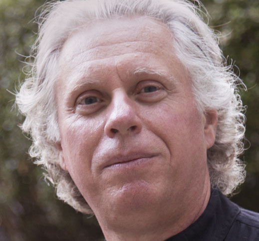 Portrait of James Trofatter. He is an elderly man with blown back white hair, cleanly shaved. He wears a slight grin.